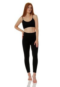 Top crop noir et leggings taille haute, en tissu extensible. Texture lisse avec fines bretelles et silhouette ajustée.