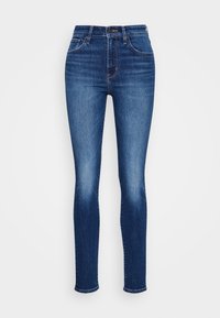 Jeans ajustados de tiro alto en azul, con una textura de denim suave, detalles de desvanecimiento cerca de los muslos y un diseño de cinco bolsillos; cierre de botón metálico.