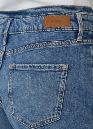 Blauwe denim jeans hebben een bruine leren merkpatch, subtiele stiksels en een klassiek zakontwerp aan de achterkant.