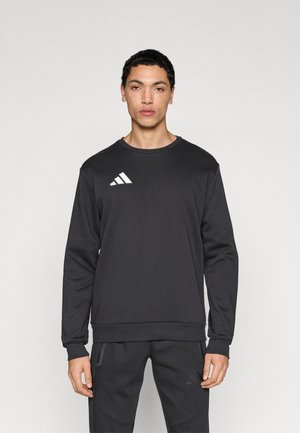 Sweat-shirt noir à manches longues, col rond et poignets côtelés. Présente un logo Adidas blanc sur le côté gauche de la poitrine. Confectionné dans un tissu lisse.