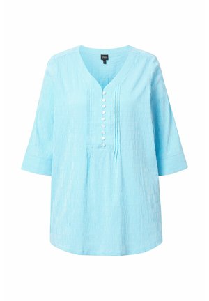 Túnica de color azul claro con rayas verticales blancas, con escote en V, mangas tres cuartos y una fila de botones blancos en el frente.