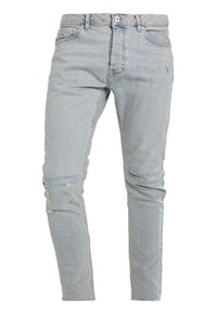 Jeans de mezclilla azul claro con corte slim, que presentan detalles desgastados y roturas en las rodillas. Diseño clásico de 5 bolsillos con cremallera.