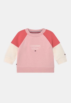 Bluza dla niemowląt z różowym korpusem, czerwonymi górnymi rękawami, kremowymi dolnymi rękawami oraz tekstem i logo "tommy hilfiger" na przodzie.