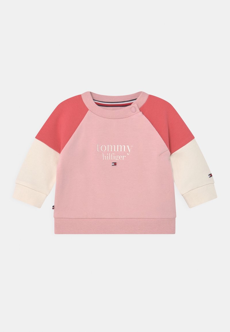 Sweatshirt pour bébé avec corps rose, manches supérieures rouges, manches inférieures crème, avec le texte "tommy hilfiger" et le logo sur le devant.