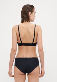 Čierny bikinový set s elegantným dizajnom. Vrchný diel má nastaviteľné ramienka a háčikové zapínanie, zatiaľ čo spodný diel je nízko strihaný s minimalistickým pokrytím.