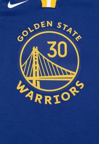 Modrý sportovní dres s kruhovým logem, na kterém je žlutá grafika mostu, nad ním nápis "GOLDEN STATE", uprostřed číslo "30" a níže "WARRIORS".