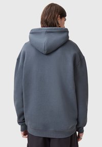 Felpa con cappuccio in tessuto blu-grigio scuro. Presenta una vestibilità comoda, polsini a costine e una tasca a marsupio. Texture liscia con un design casual.