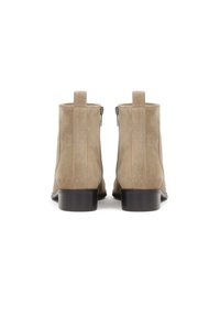 Beżowe zamszowe botki za kostkę o gładkiej fakturze, z niskim obcasem i zamkiem po obu stronach ułatwiającym zakładanie.