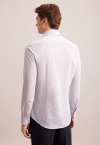 Lichtgrijs geruit overhemdd met een spread collar, lange mouwen, knoopmanchetten en een afgeronde zoom.