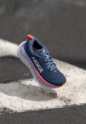 Blauwe sportschoen met een gestructureerde bovenkant, voorzien van een witte en paarse zool en oranje accenten. Inclusief een merkembleem en vetersysteem.