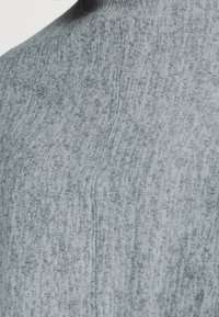 Light gray sweater with a textured knit pattern, high neckline, and visible seam detail. Soft material with a comfortable appearance.