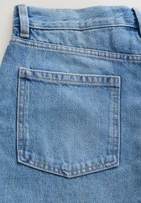 Poche arrière d'un jean en denim bleu montrant la texture du tissu, les coutures orange, les passants de ceinture et les détails de la ceinture.