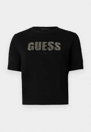 Pulover negru cu mâneci scurte, cu decolteu și manșete din material tricotat cu dungi, având inscripțiile "GUESS" și "EST. 1981" realizate din ținte metalice pe partea din față.