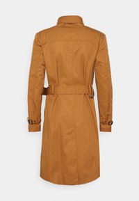 Cappotto lungo marrone realizzato in un tessuto liscio e leggermente testurizzato. Presenta una cintura in vita, polsini con bottoni e un collo classico.