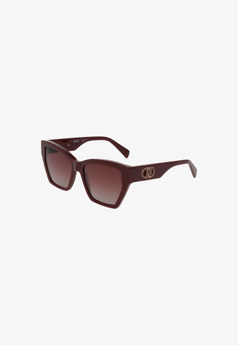 Occhiali da sole a forma quadrata bordeaux con lenti marroni sfumate. Presentano montature spesse e un accento dorato con logo sulla tempia.