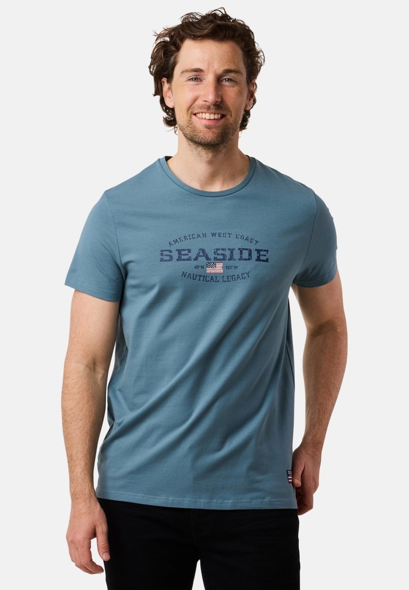 Blue cotton t-shirt with short sleeves, featuring "SEASIDE" graphic print in dark blue and a small American flag detail.