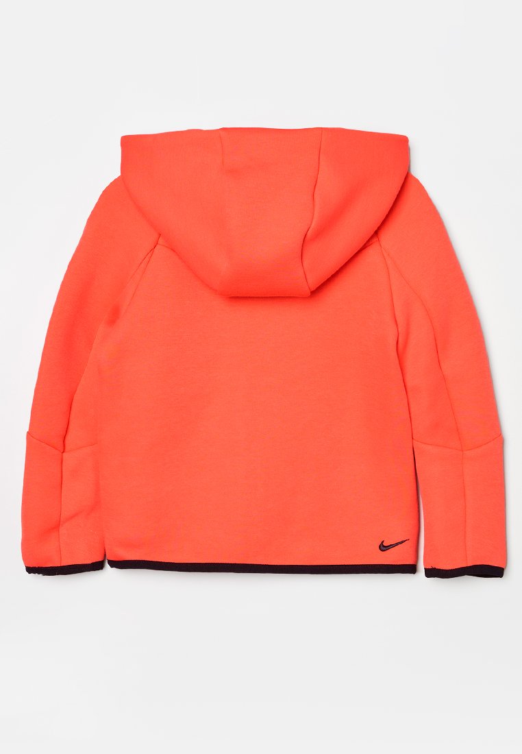 Pomarańczowa bluza z kapturem i długimi rękawami, wykonana z miękkiego materiału. Posiada czarne logo Nike na dolnym obrzeżu oraz kontrastowe granatowe mankiety.