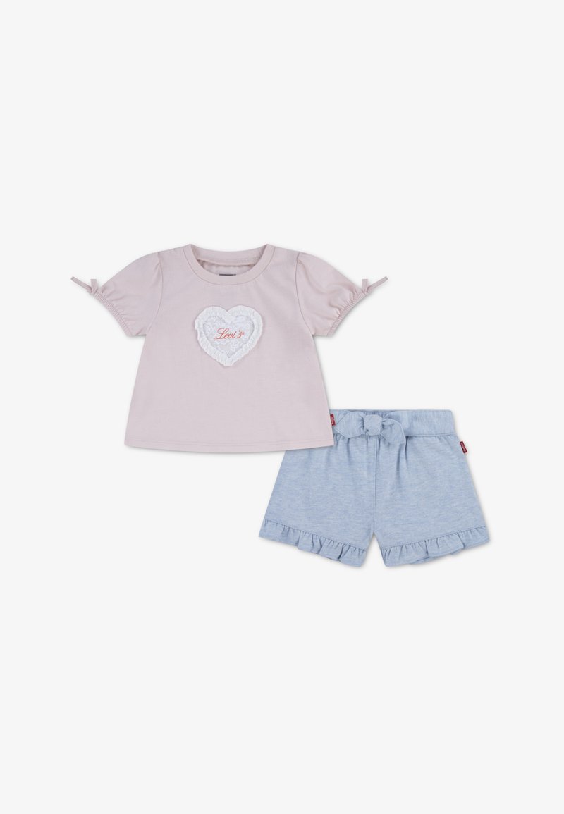 Haut rose clair à manches courtes avec un patch en dentelle blanche en forme de cœur et le texte "Levi's". Short bleu avec ourlet à volants et taille à cordon.