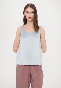 Lichtblauw satijnen tanktop met een ronde hals en een relaxte pasvorm, gecombineerd met losse, roze broeken. Gladde textuur, minimalistisch ontwerp.
