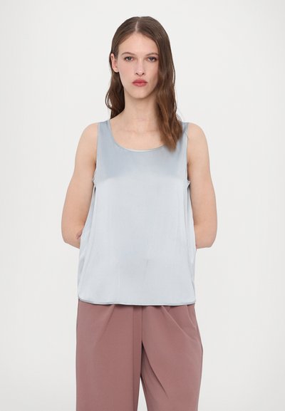 Camisola satin azul clara com decote redondo e corte folgado, combinada com calças largas rosas. Textura suave, design minimalista.