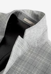 Chaqueta de cuadros gris con cuello de lana y forro interior negro. Presenta una tela texturizada y líneas limpias en un diseño entallado.