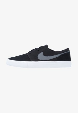 Zwarte suède sneakers met een grijze Nike swoosh, voorzien van een witte rubberen zool en een klassiek vetersysteem. Gladde textuur en gestroomlijnde vorm.