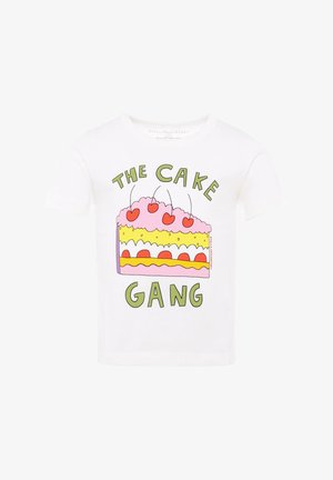T-shirt en coton blanc présentant un graphique coloré de gâteau avec un glaçage rose, des cerises rouges et un texte vert indiquant "LE GANG DES GÂTES".