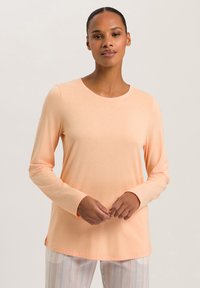 Langarm, ronde hals t-shirt van zachte perzikkleurige stof met een gladde textuur. Bevat zijslits en licht getailleerde mouwen.