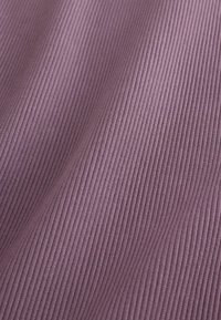 Gros plan sur la texture d'un tissu côtelé de couleur violette douce, montrant des lignes verticales et des plis doux.