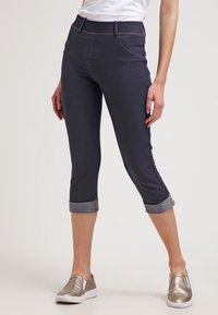 Mörkblå knälånga jeans i denim med smal passform, uppviftade byxben med ljusa denimdetaljer, samt framfickor med sömnadsdetaljer.