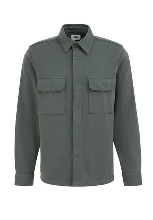 Žalias mygtukų užsegamas marškinėlis su apykakle, dviem krūtinės kišenėmis, spaudekomis ir ilgomis rankovėmis su manšetėmis. Minkšta audinio struktūra.