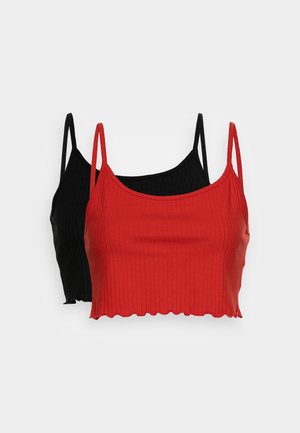 To ribbede cropped cami-toppe med tynde stropper, den ene i klart rødt foran og den anden i sort bagved, på en ensfarvet lys baggrund.