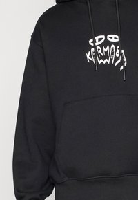 Black hooded sweatshirt featuring a front pocket, drawstrings, and a white graphic design with the word "KERM" integrated into it.