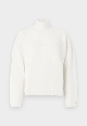 Bijeli pleteni pulover s visokim ovratnikom, s teksturiranim uzorcima na prsima i rebrastim manžetama i rubom. Mekani materijal.