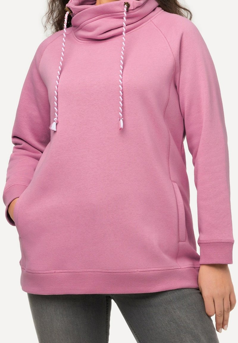 Sweatshirt rose avec un col montant et des cordons en tresse blancs. Comprend des poches latérales et des poignets côtelés, en tissu doux et texturé.
