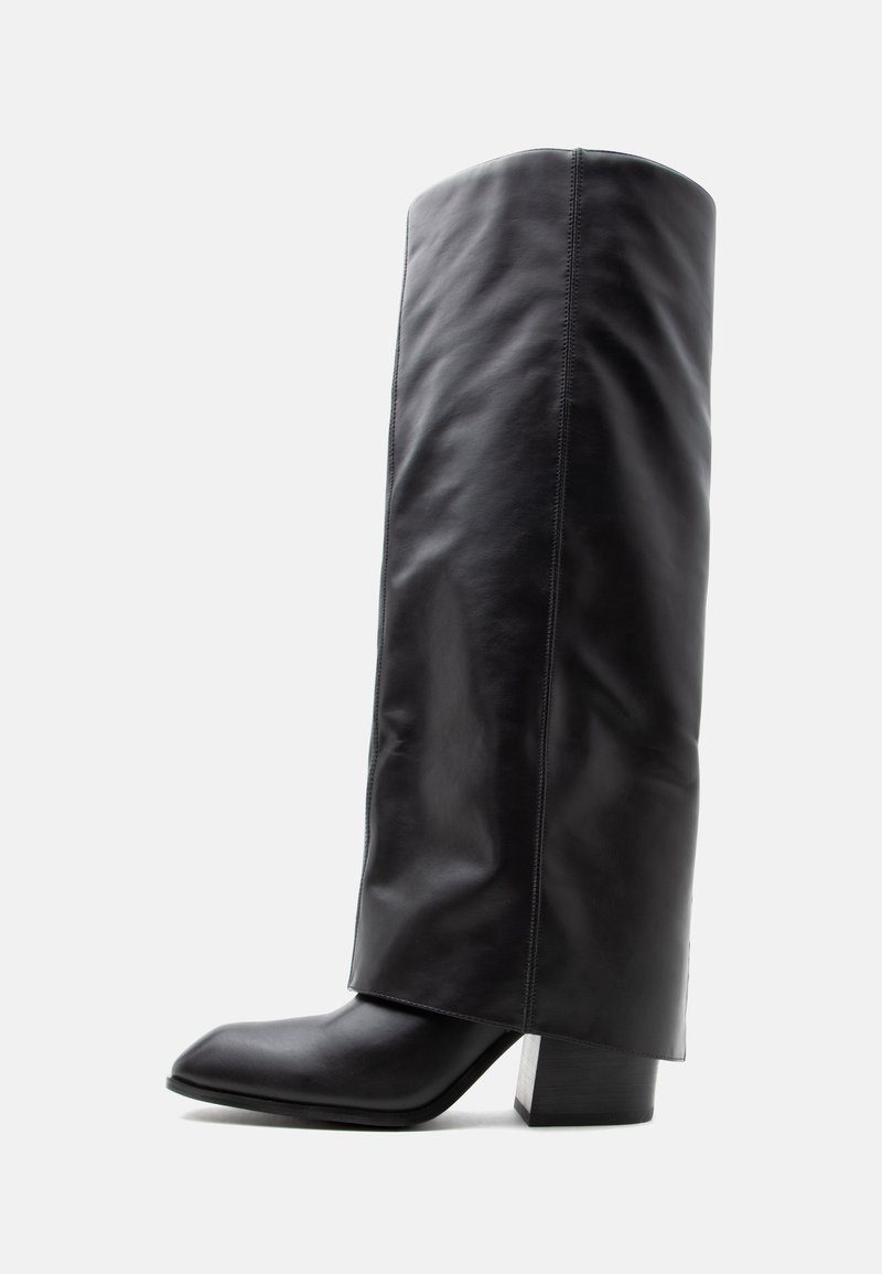 Botte haute en cuir noir avec bout carré et talon épais, vue de côté sur un fond clair uni.