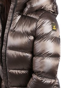 Metalen bronzen pufferjack met capuchon, voorzien van doorgestikte delen en een zwarte ritssluiting. Het logolabel op de schouder zorgt voor een merkdetail.