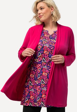 Fuchsia cardigan over a patterned dress featuring colorful, angular designs in shades of purple, red, and white, with a v-neckline.