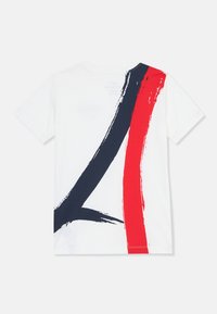 White t-shirt with short sleeves and a back design featuring large brushstroke accents in navy and red. Smooth cotton texture.