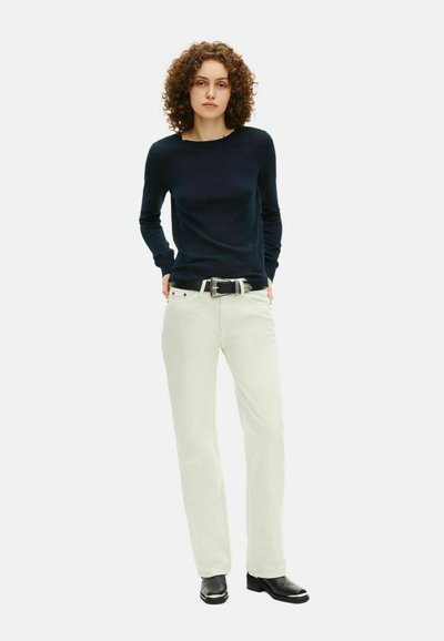 Maglione navy a maglia abbinato a pantaloni crema chiaro. I pantaloni presentano un taglio a gamba dritta e una cintura nera con fibbia metallica.