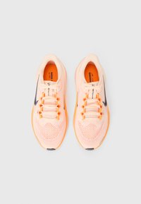 Baskets de course en maille pêche clair avec des accents orange, logo swoosh noir et lacets plats. Col rembourré pour le confort. Semelle extérieure en caoutchouc.