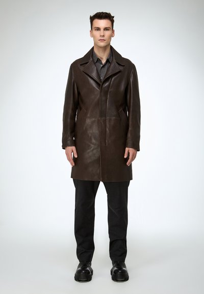 Brauner Ledermantel mit Reverskragen, Frontreißverschluss und zwei Seitentaschen. Trägt man über einem dunklen Hemd, kombiniert mit schwarzer Hose und schwarzen Schuhen.