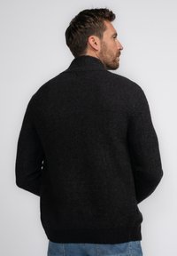 Donkergrijze gebreide cardigan met een hoge kraag, geribbelde textuur en een ontspannen pasvorm. Kenmerkt zich door lange mouwen en een effen kleurontwerp.