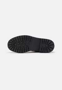 Suela de zapato de goma negra con patrones de banda de rodadura profundos y resistentes. Presenta formas hexagonales y angulares para un mejor agarre. Acabado duradero y texturizado.