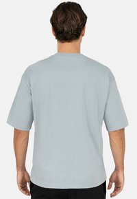 T-shirt bleu clair à manches courtes avec col rond, en coton doux, doté d'une coupe décontractée et d'une texture unie. Aucun motif ou accent notable.