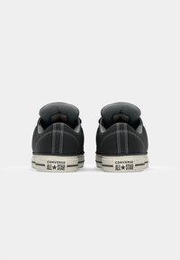 Black canvas low-top sneakers with gray accents, white rubber soles, contrasting stitching, and "Converse All Star" logo on the heel.