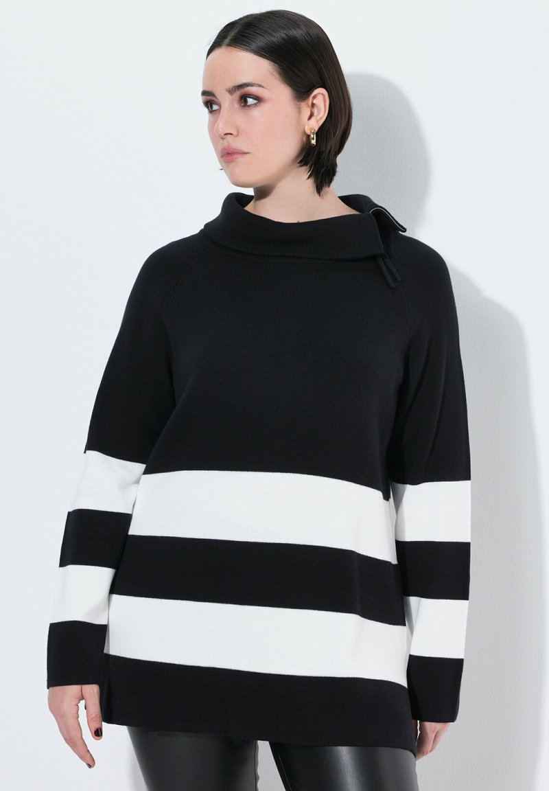 Suéter de punto de rayas en blanco y negro con cuello de cowl, mangas largas, textura acanalada y corte holgado. Patrón horizontal distintivo.