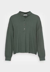 Camisa de manga larga verde oscuro de corte relajado, con botonera y cuello alzado; hecha de material suave y ligero.