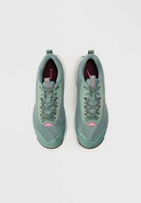 Baskets de course Nike avec une tige en tricot vert, des accents roses et une semelle extérieure marron. Comprend des lacets et un design ergonomique pour plus de confort.