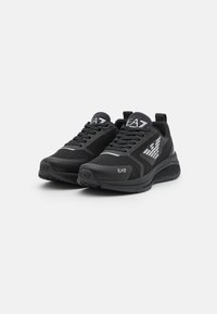 Zapatillas deportivas negras con parte superior de malla y sintético, puntera redondeada, cordones finos, suela de goma y acentos en blanco del logo a los lados.